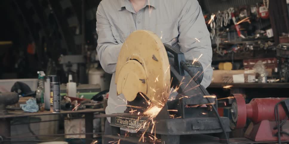 Man in a workshop uses an abrasive saw generating intense sparks