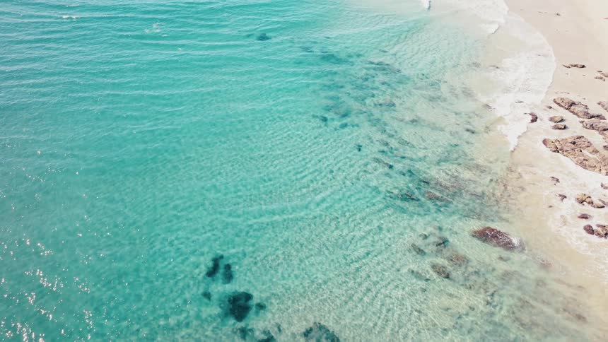 Aerial view of a beach with a sea of crystal clear waves