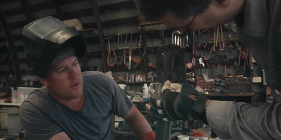 Coworkers discuss a welding task while in a workshop