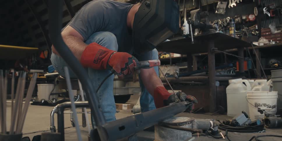 A person in protective gear is welding metal pieces together with bright sparks flying