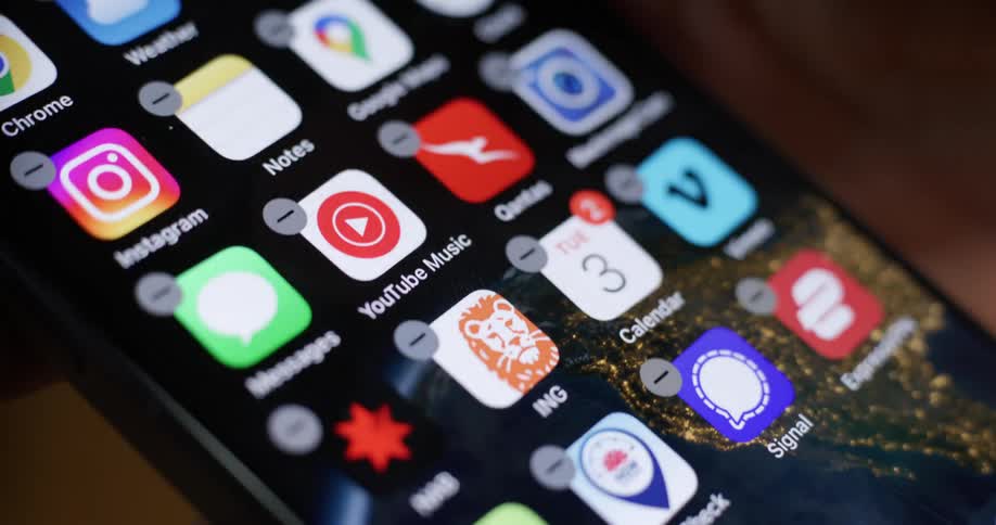 A finger pressing the delete button on an iphone screen with the instagram app highlighted and a message indicating that it will be removed from the home screen