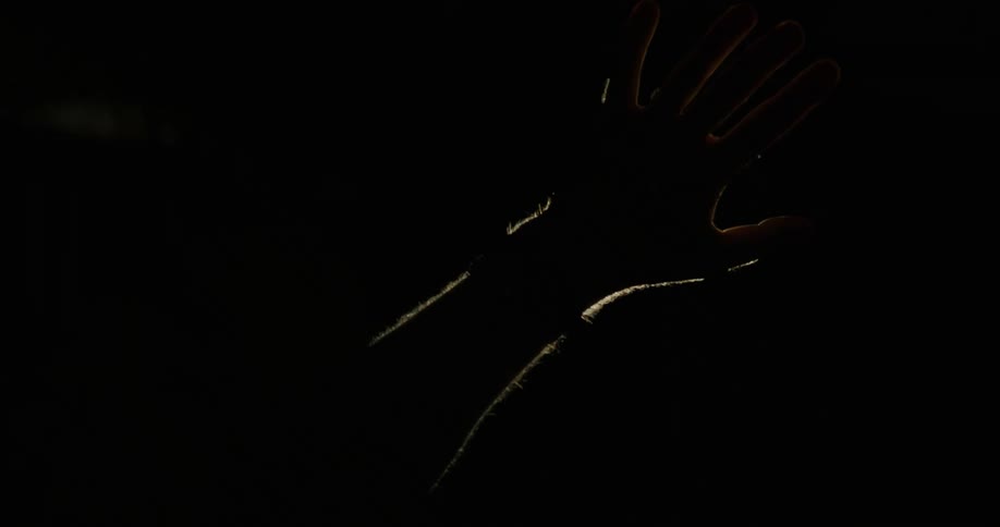 The hand of a person placing it in front of a strong light on the ceiling in a dark room