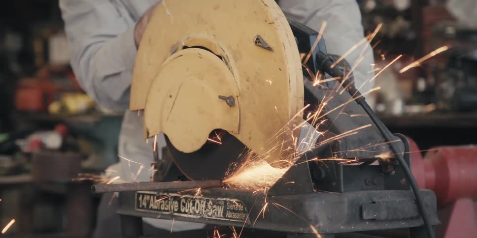 Sparks fly as a circular saw cuts through a metal bar