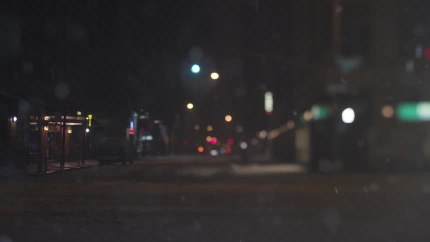 Snow falls at night in a city