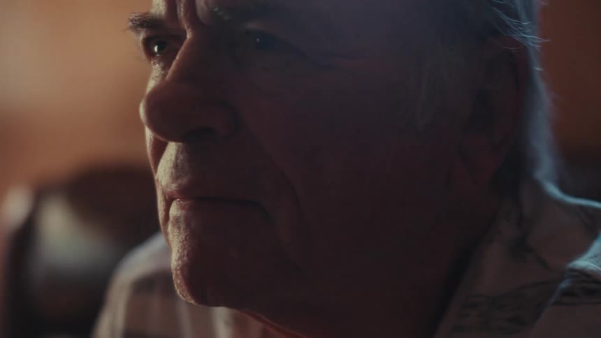 Elderly man looking forward while sitting on a sofa