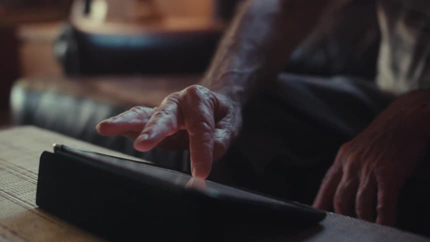 A man taps on the tablet screen at home