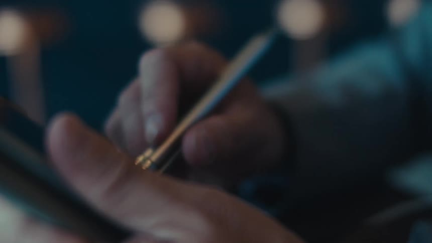 A hand using a stylus pen to interact with a tablet device
