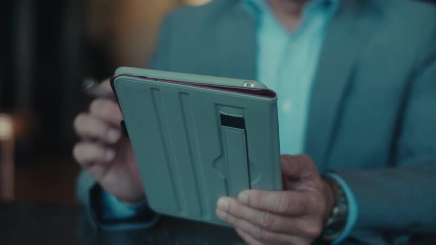 A man is using a stylus on his tablet