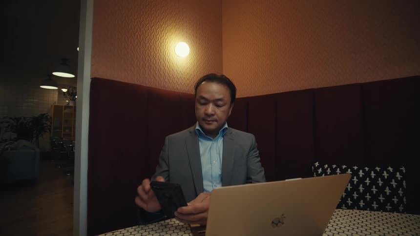 A man stops typing to pick up his cell phone