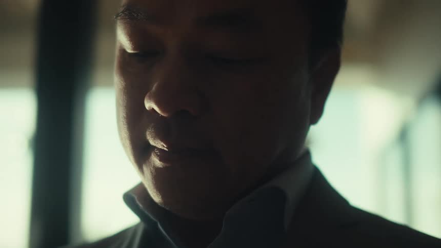 A man in a business suit thinking and taking notes on a modern office