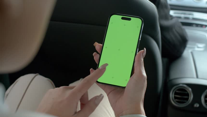A woman answers her phone in the back seat of the car