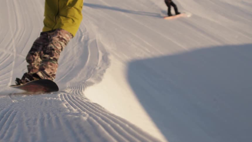 A man rides a snowboard on heavily packed snow