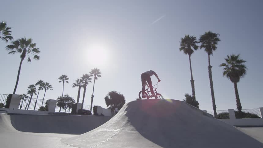 Bike rider riding over a jump at a skate park near the beach