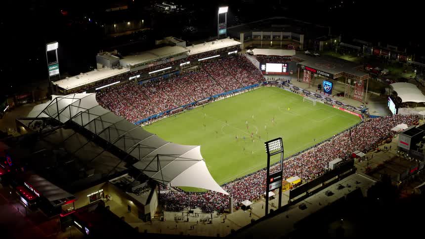 An aerial view of a packed soccer stadium during a match with a large crowd filling the stands
