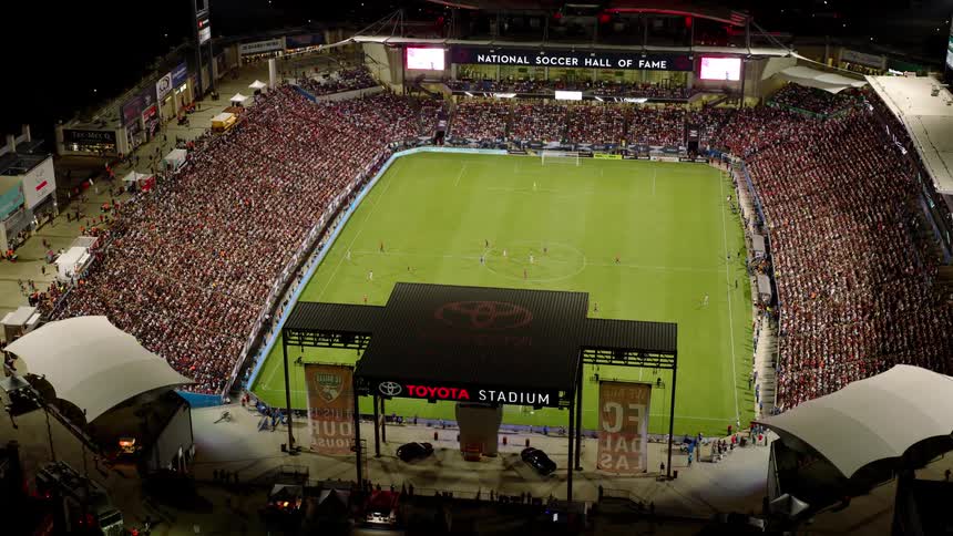 An aerial view of a packed soccer stadium during a match with a large crowd filling the stands