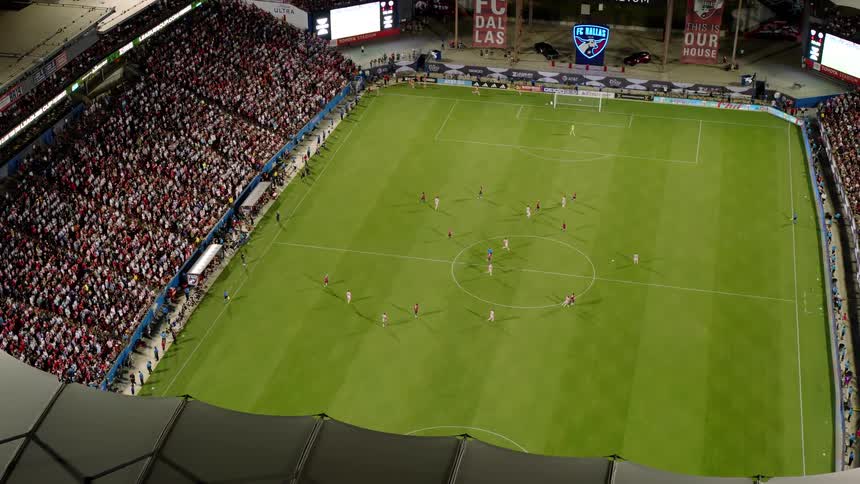 A soccer match is being played in a stadium filled with cheering fans