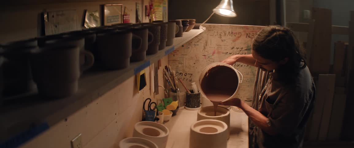 A longhaired man pouring material into a ceramics mold