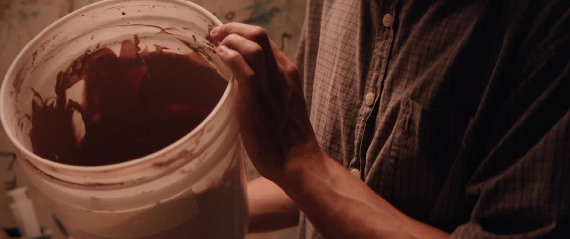 A person mixing bucket of clay before pouring into a cast