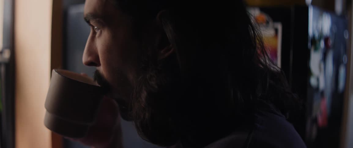 Man drinks coffee while looking out the kitchen window
