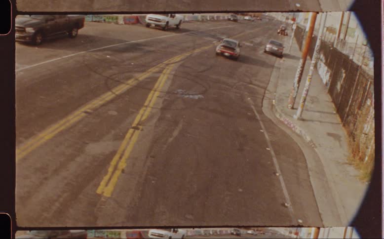 A street scene with a gray sports car passing under a bridge