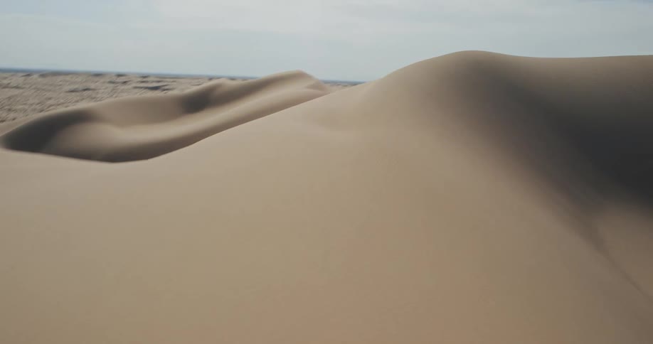 Dunes under a partially overcast sky contain shadowy depressions