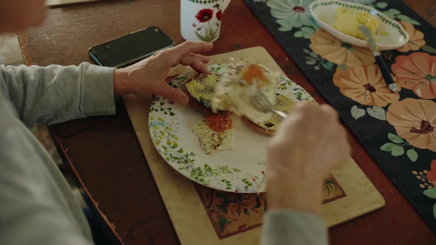 A person scoops eggs onto her toast to eat
