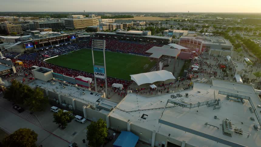 An aerial view of a stadium with a lawn and the stands full of people