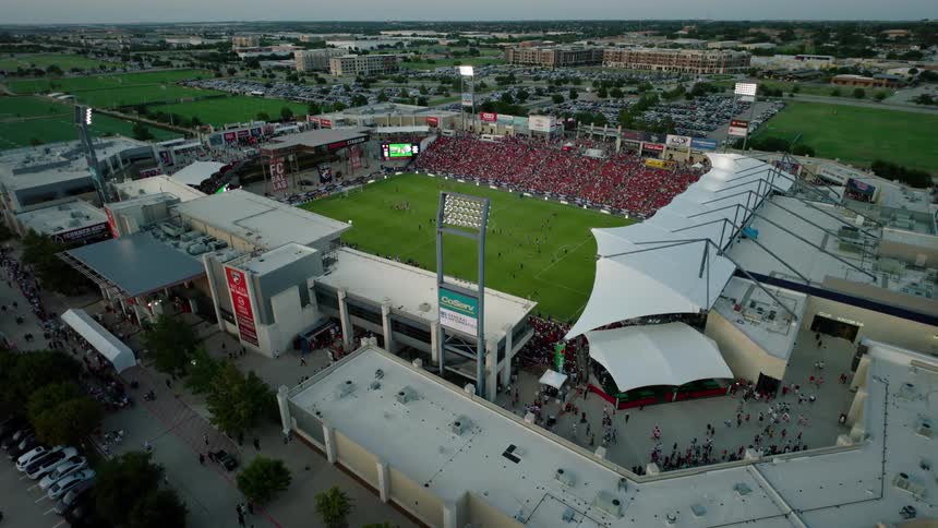 An aerial view of a packed soccer stadium during a match with a large crowd filling the stands