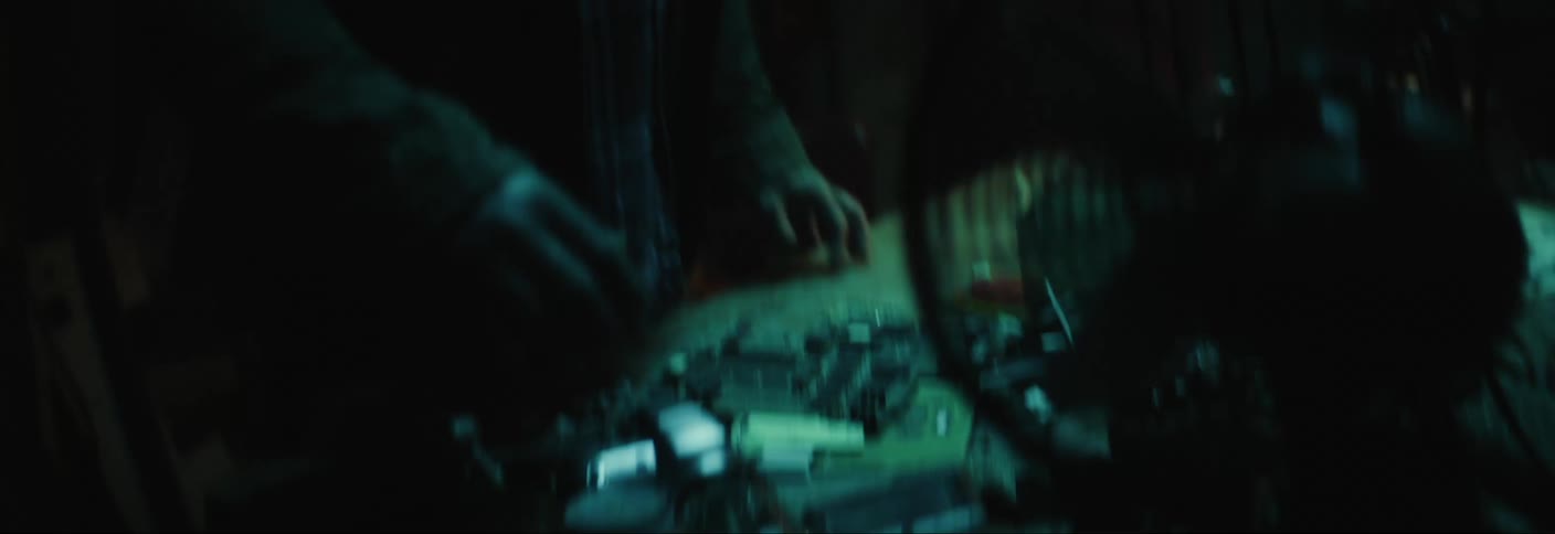 A disheveled man with long hair grabs a crowbar from a cluttered table in a dark basement and heads up the stairs