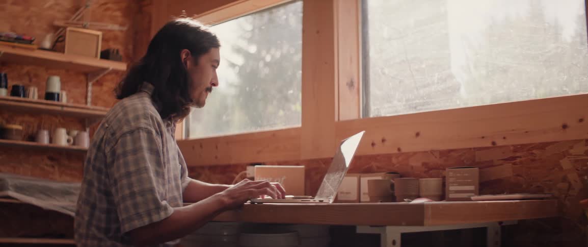 A man is smiling while he types on the laptop