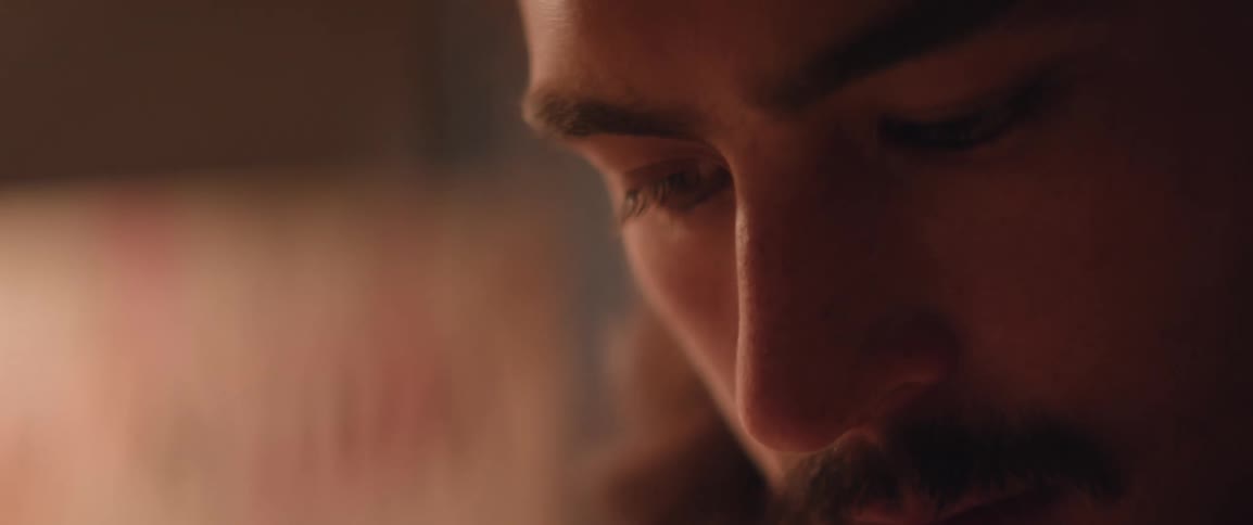 The face of the young man with a mustache looking down while working