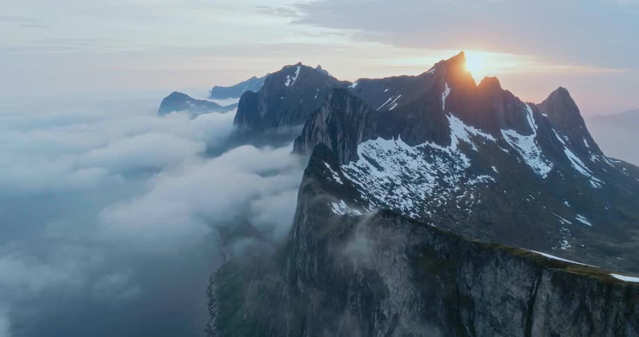 A mountain surrounded by clouds during sunset