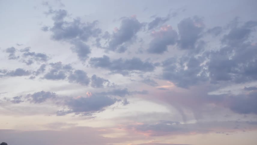 A sky filled with wispy pastelcolored clouds at dawn