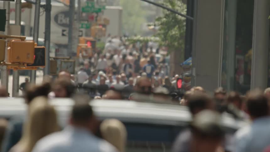 Many people are walking on the sidewalk in the city