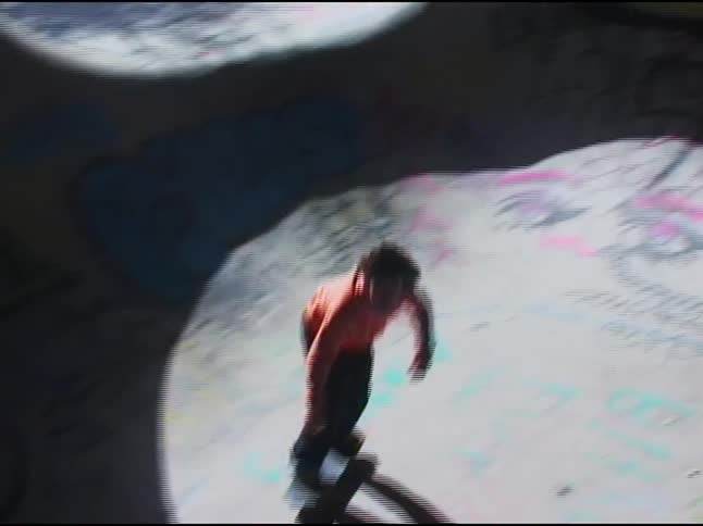 A teenager is riding on the ramps with a skateboard