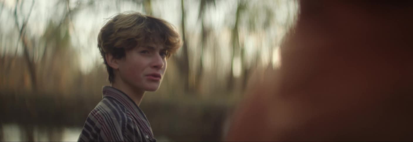 A clip pf a boy talking with someone and throwing a rock