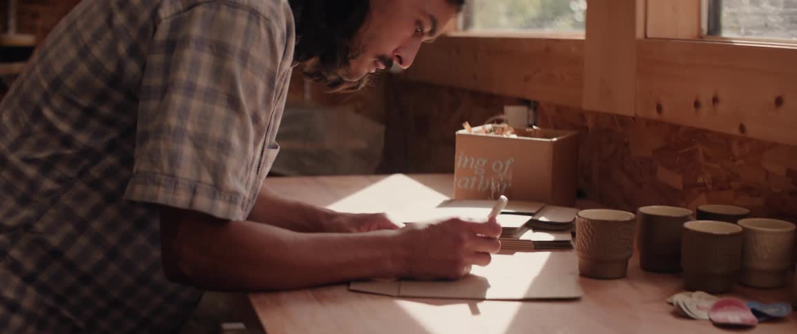 Man writing while standing at a workshop bench