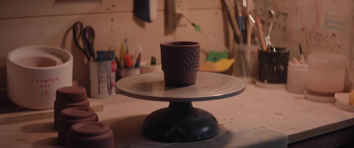 Hand carved ceramic cup sitting on a pottery wheel