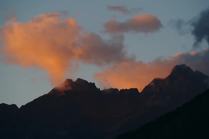 Sunlight shines on clouds over a mountain ridge
