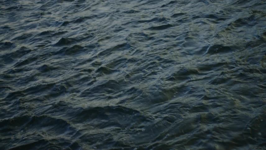 The dark rippling water of a river flows beneath a cloudy sky