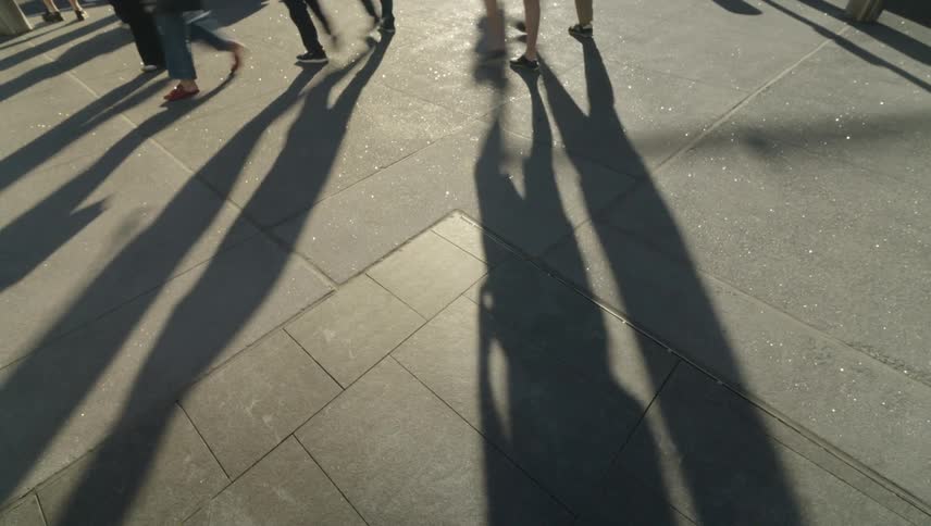 People give off shadows as they walk on the sidewalk