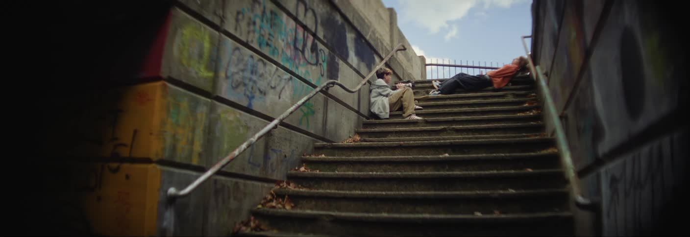 A person lying down and another person sitting on the steps of a staircase leading to a terminal