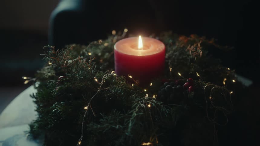 A candle is burning inside the wreath