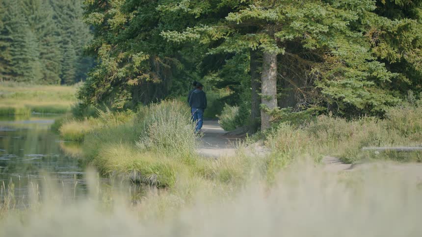 Two men hike on a path by the forest