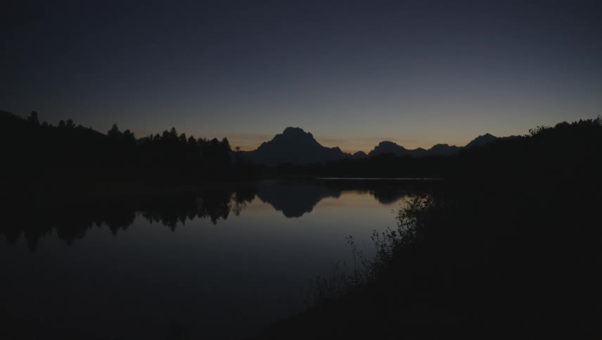 The sun is setting on the lake and forest