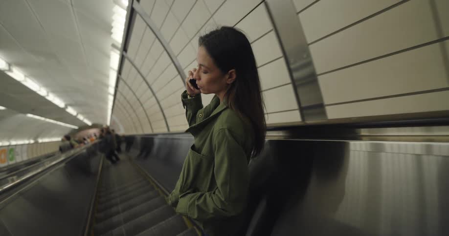 Woman on a phone call while going down an escalator