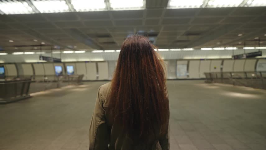 A woman walks through a modern welllit empty subway station
