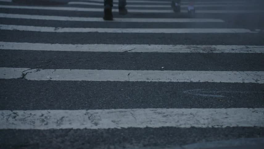 Legs of two people crossing a pedestrian crossing