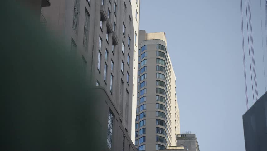 A towering skyscraper with a facade of uniform windows reaching towards a clear blue sky