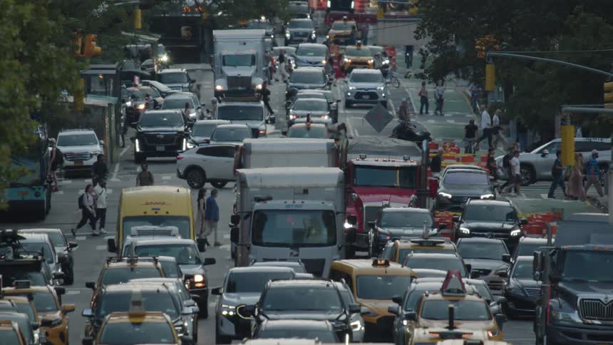 A congested city street is filled with a variety of vehicles including cars and trucks creating a chaotic scene of bumpertobumper traffic